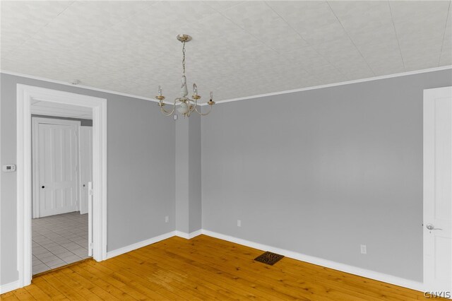 empty room with light tile patterned flooring, crown molding, and an inviting chandelier