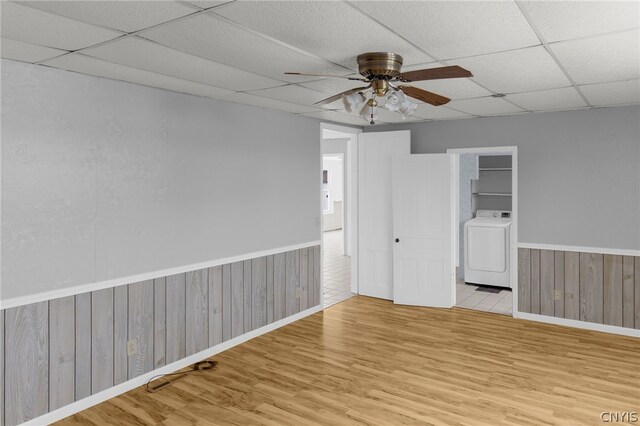 spare room featuring washer / clothes dryer, light hardwood / wood-style floors, a drop ceiling, and ceiling fan