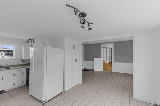 kitchen featuring black dishwasher, sink, light tile patterned floors, white cabinetry, and white fridge with ice dispenser