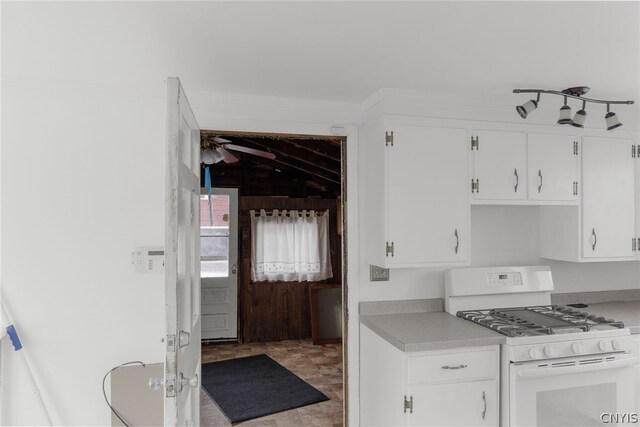 kitchen with tile patterned floors, white cabinetry, white gas range oven, and track lighting