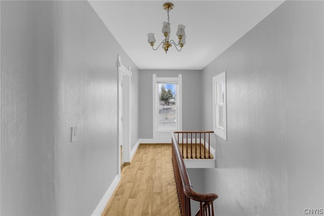 hallway featuring an inviting chandelier and light wood-type flooring