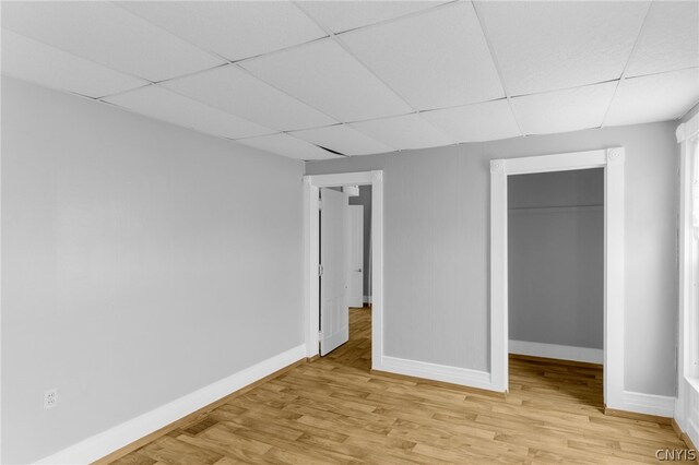 unfurnished bedroom featuring light hardwood / wood-style floors, a drop ceiling, and a closet