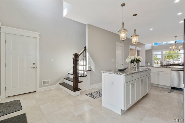 kitchen with light tile floors, hanging light fixtures, white cabinets, stainless steel dishwasher, and light stone countertops