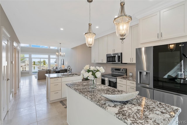 kitchen featuring white cabinets, stainless steel appliances, decorative light fixtures, and light stone counters