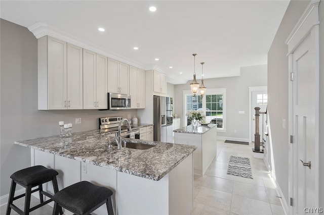 kitchen featuring decorative light fixtures, stone counters, light tile flooring, appliances with stainless steel finishes, and white cabinets