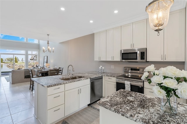 kitchen featuring white cabinets, light stone counters, appliances with stainless steel finishes, and sink