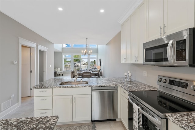 kitchen with an inviting chandelier, appliances with stainless steel finishes, white cabinets, and kitchen peninsula