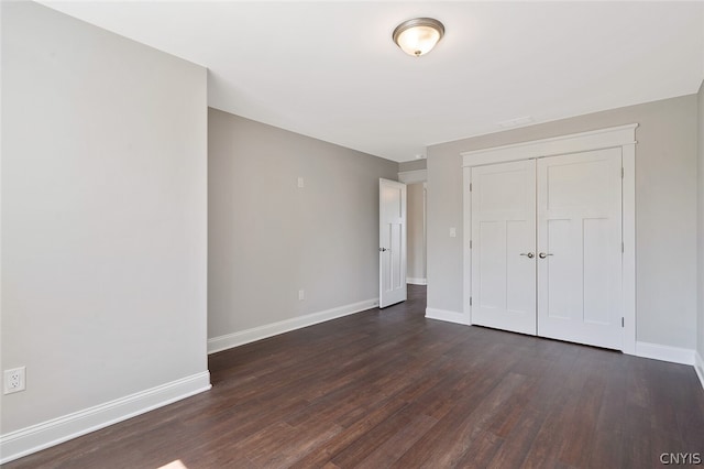 unfurnished bedroom featuring a closet and dark hardwood / wood-style flooring