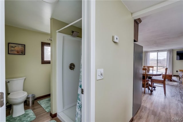 bathroom with hardwood / wood-style floors, toilet, and curtained shower