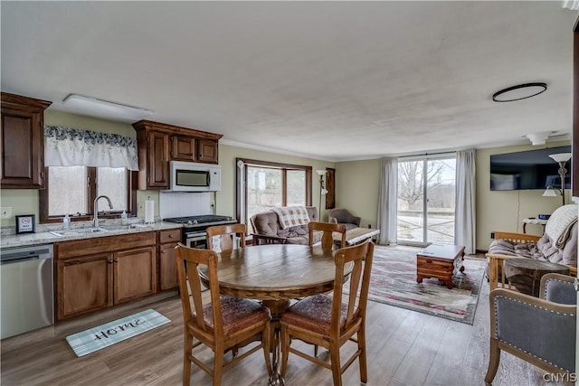 dining room with sink, ornamental molding, plenty of natural light, and light wood-type flooring