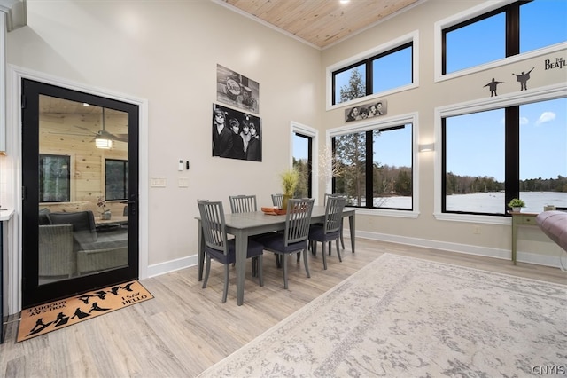 dining room featuring a high ceiling, wooden ceiling, ornamental molding, and light hardwood / wood-style flooring