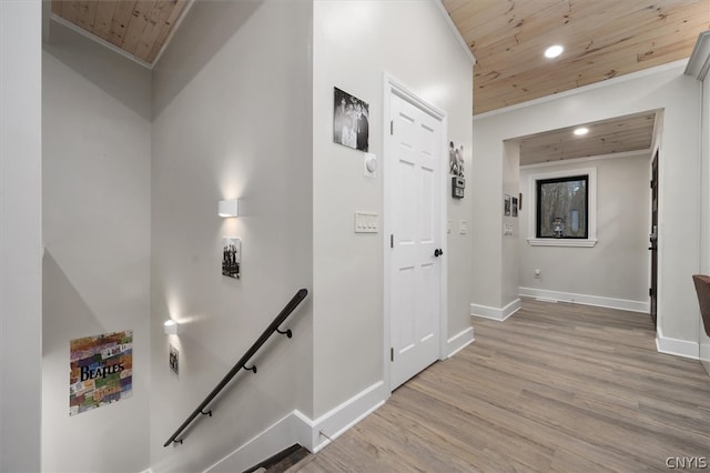 corridor with light hardwood / wood-style floors, wood ceiling, and ornamental molding