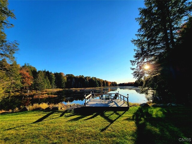 view of dock with a yard and a water view