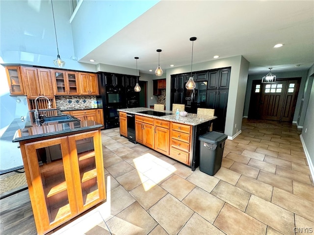 kitchen with black electric stovetop, decorative backsplash, light stone countertops, and a kitchen island