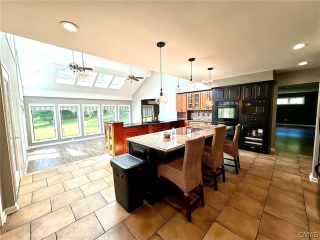 interior space featuring light tile patterned flooring, vaulted ceiling with skylight, sink, and ceiling fan