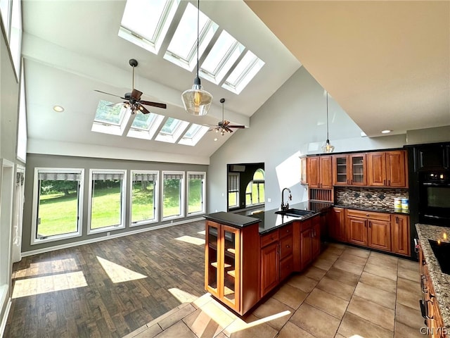 kitchen with oven, decorative backsplash, a skylight, high vaulted ceiling, and ceiling fan