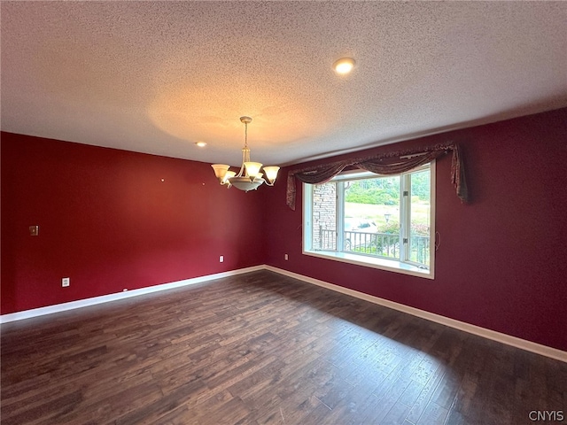 spare room featuring a textured ceiling, wood-type flooring, and a notable chandelier