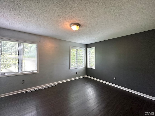 unfurnished room with dark wood-type flooring and a textured ceiling