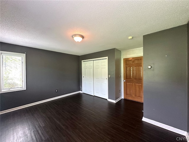 unfurnished bedroom with a closet, a textured ceiling, and dark wood-type flooring