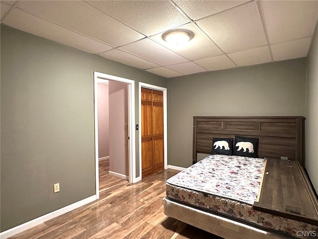 bedroom with hardwood / wood-style floors, a closet, and a drop ceiling