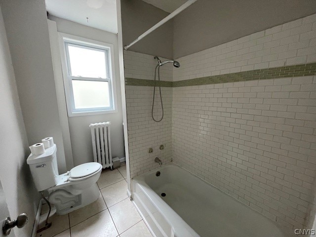 bathroom featuring toilet, tiled shower / bath, tile patterned floors, and radiator