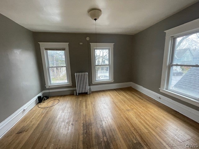 unfurnished dining area featuring a wealth of natural light, radiator heating unit, and light hardwood / wood-style floors