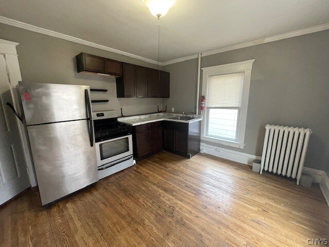 kitchen with stainless steel refrigerator, electric stove, radiator heating unit, and light hardwood / wood-style flooring