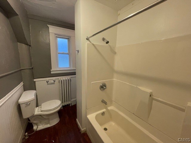 bathroom with radiator, hardwood / wood-style floors, shower / bathing tub combination, and toilet