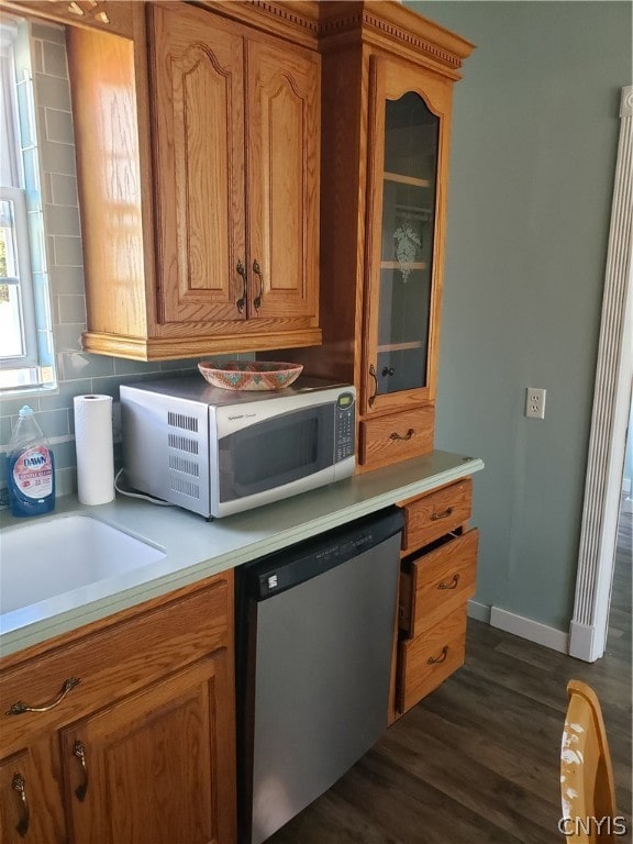 kitchen with appliances with stainless steel finishes, backsplash, dark wood-type flooring, and sink