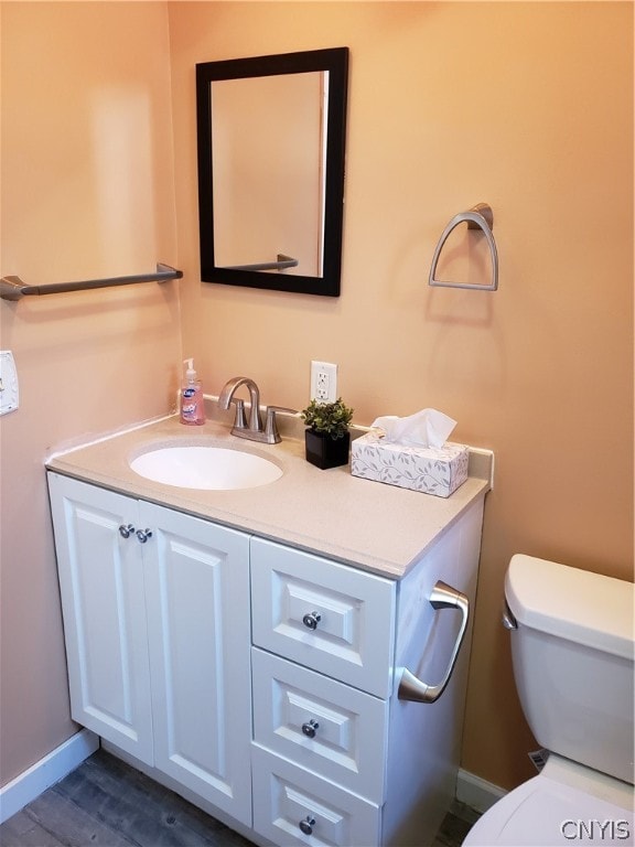 bathroom featuring toilet, vanity, and wood-type flooring