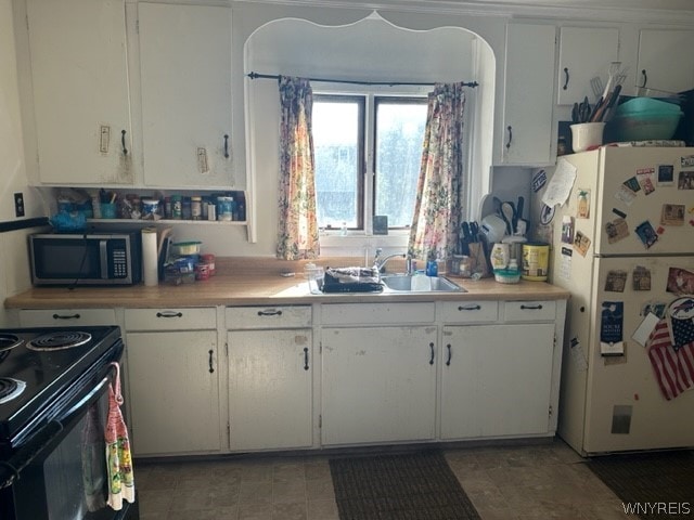 kitchen featuring white cabinets, white refrigerator, light tile flooring, and sink