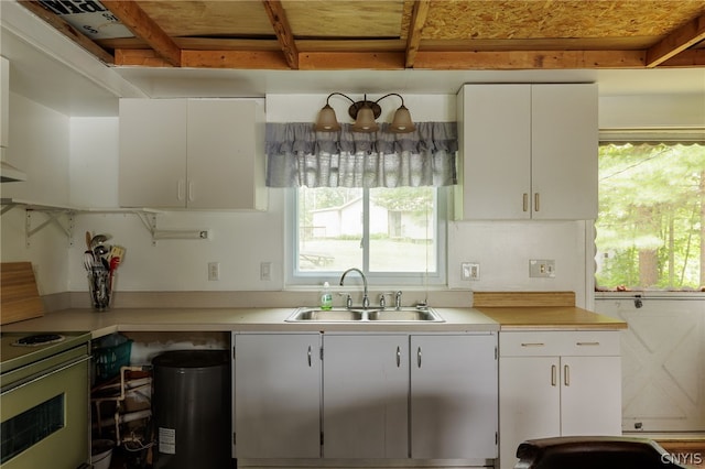 kitchen with electric range, plenty of natural light, sink, and white cabinetry