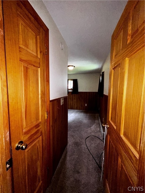 hall with a textured ceiling and dark carpet