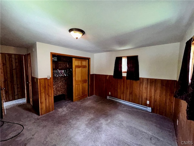 unfurnished bedroom featuring dark carpet, a closet, and a baseboard heating unit