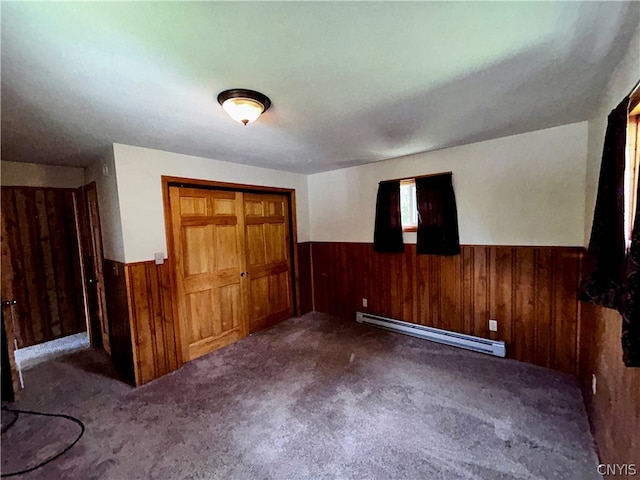 unfurnished bedroom featuring baseboard heating, a closet, and dark carpet