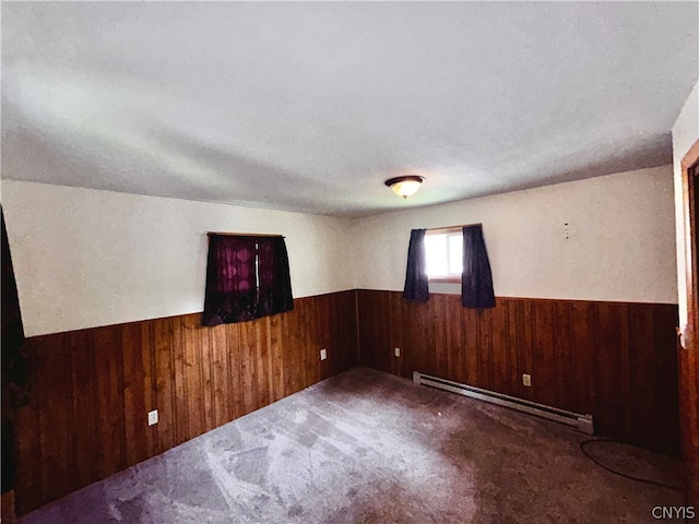 unfurnished room with wooden walls and a baseboard radiator