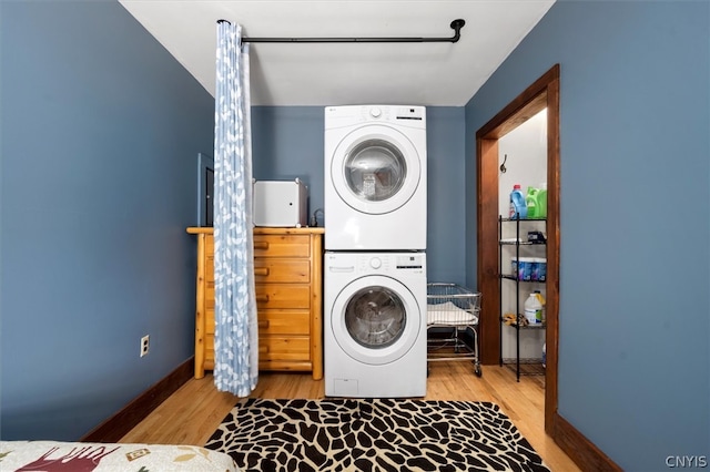 clothes washing area featuring stacked washer / drying machine and light hardwood / wood-style flooring