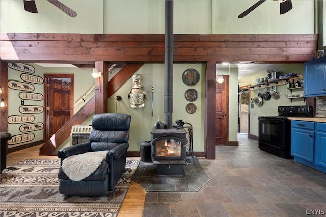 tiled living room featuring ceiling fan and a wood stove