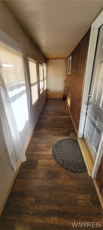 hallway featuring dark hardwood / wood-style flooring and wood walls