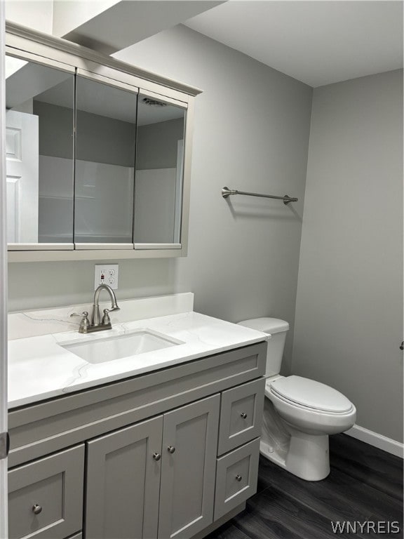 bathroom with hardwood / wood-style flooring, toilet, and vanity with extensive cabinet space