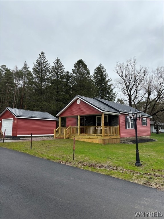 view of front of house featuring a front lawn, covered porch, an outdoor structure, and a garage