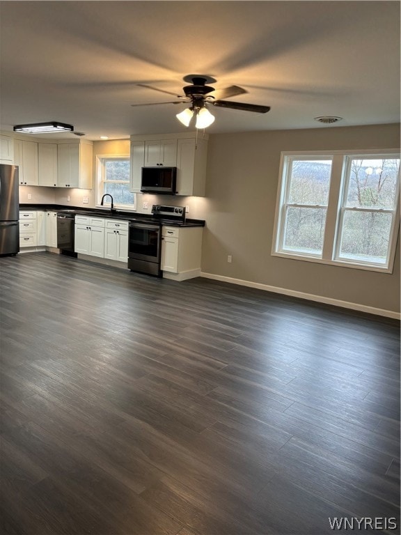 kitchen with ceiling fan, dark wood-type flooring, stainless steel appliances, and white cabinets