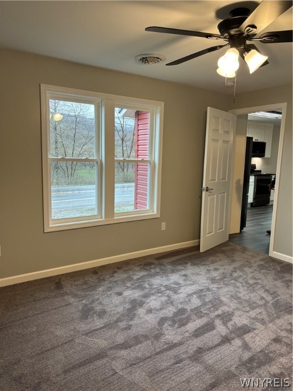 carpeted empty room featuring a healthy amount of sunlight and ceiling fan