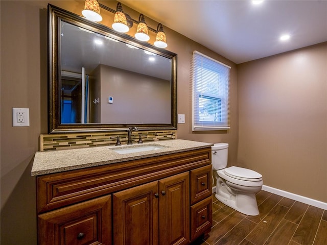 bathroom with hardwood / wood-style flooring, tasteful backsplash, vanity, and toilet