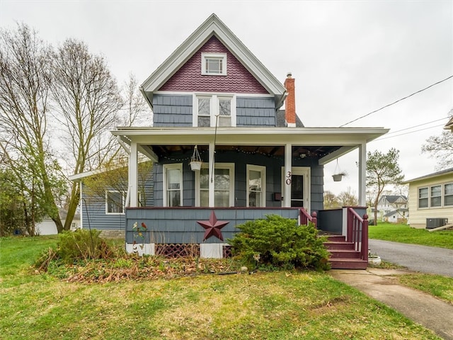 view of front facade with central AC unit, a porch, and a front yard