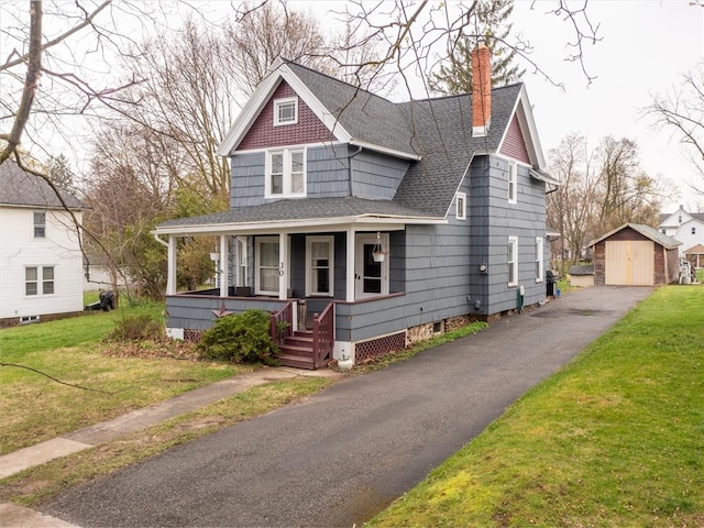 view of front of property featuring a porch, a front lawn, and an outdoor structure