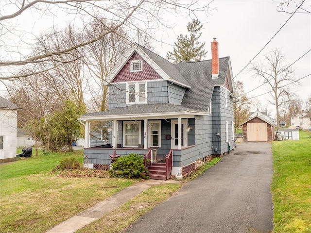 view of front facade featuring a porch, an outdoor structure, and a front yard