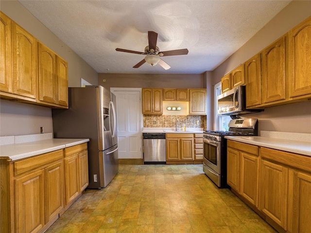 kitchen featuring appliances with stainless steel finishes, ceiling fan, light tile floors, sink, and backsplash