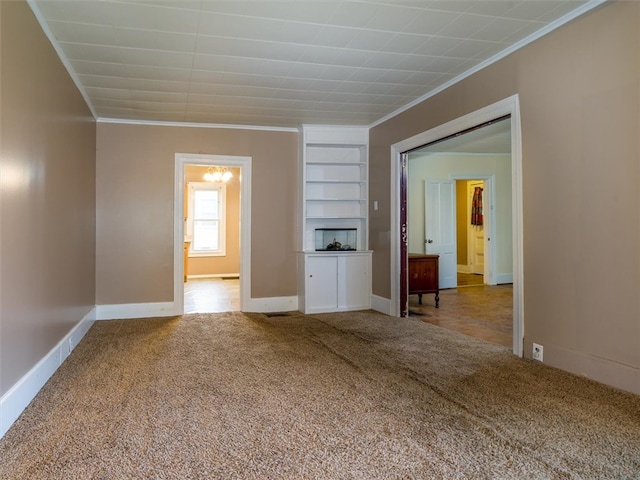 interior space featuring built in shelves, ornamental molding, and light colored carpet