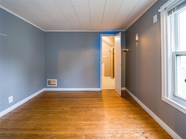 spare room featuring plenty of natural light, light hardwood / wood-style flooring, and crown molding